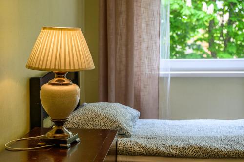 a lamp sitting on a table next to a bed at Liepu Hostelis in Liepāja