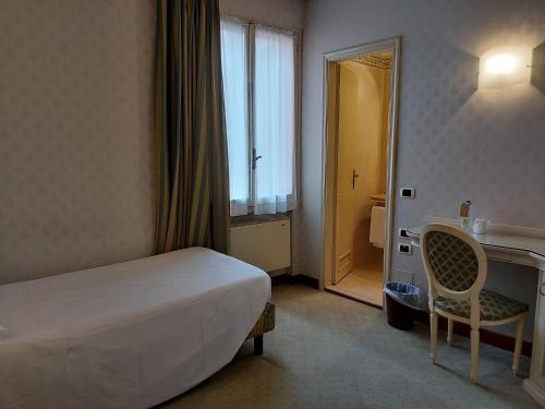 a bedroom with a bed and a desk and a chair at Phi Hotel Canalgrande in Modena