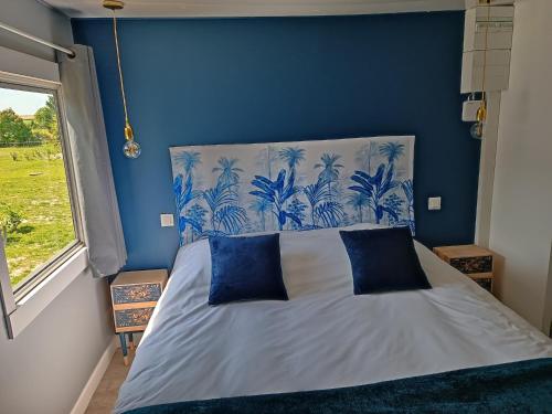 una camera blu con un letto con due cuscini blu di Domaine bulle étoilée a Rouilly-Sacey