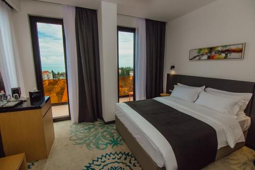 a hotel room with a large bed and large windows at Graphic Hotel Batumi in Batumi