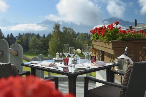 a table with wine glasses and flowers on a patio at Guarda Golf Hotel & Residences in Crans-Montana
