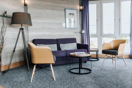 a living room with a purple couch and two chairs at Best Western Hotel Kurfürst Wilhelm I. in Kassel
