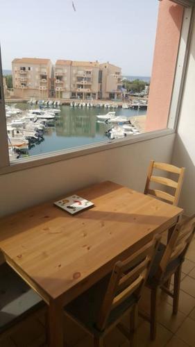 a wooden table and chairs in a room with a window at Superbe appartement avec vue sur la mer et port in Frontignan