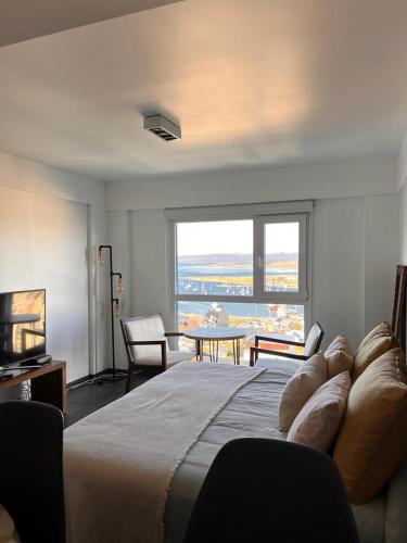 a bedroom with a large bed with a large window at LiveUshuaia Beagle View in Ushuaia