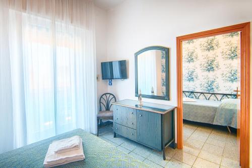 een slaapkamer met een bed, een spiegel en een dressoir bij Hotel Gorini in Bellaria-Igea Marina