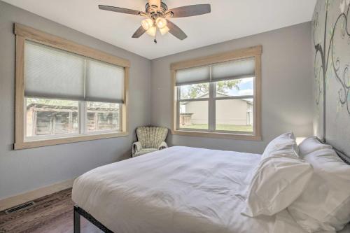 a bedroom with a bed with a ceiling fan and two windows at Idyllic Gem Screened Porch, half Mi to River! in Thermopolis