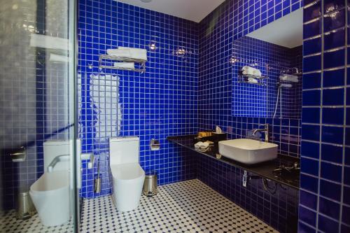 a blue tiled bathroom with two toilets and a sink at Graphic Hotel Batumi in Batumi