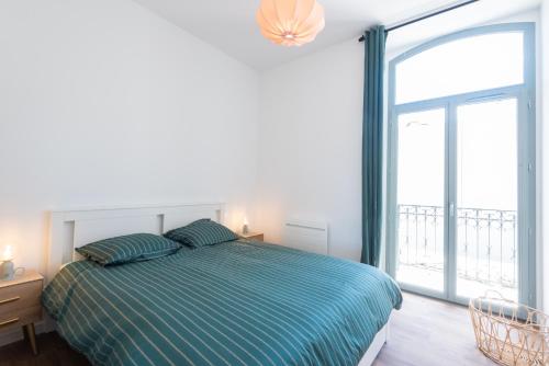 a bedroom with a bed and a large window at Appartements centre-ville - Wifi - Cuisine tout équipée - Lave-linge in Pau