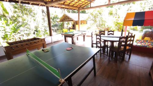a ping pong table in a room with tables and chairs at Recanto dos Pássaros - Sana Chalés in Sana
