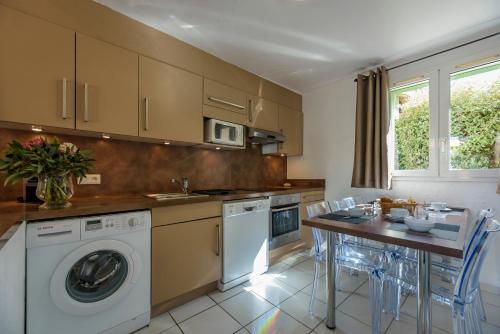 a kitchen with a washing machine and a table with chairs at Résidence Vasca d'Oro in Porto-Vecchio