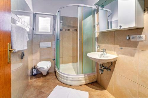 een badkamer met een douche, een wastafel en een toilet bij ERE Apartment in Srima