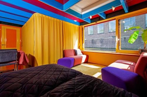 1 dormitorio con cama, sillas y ventana en Dreamtime Houseboat en Ámsterdam