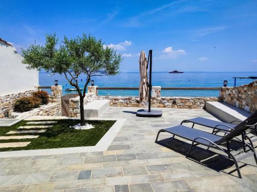 a patio with a bench and a tree and the ocean at Aura di mare luxury house Thassos in Limenas