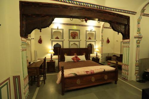 a bedroom with a bed and a desk in it at Hotel Radhika Haveli, Mandawa in Mandāwa