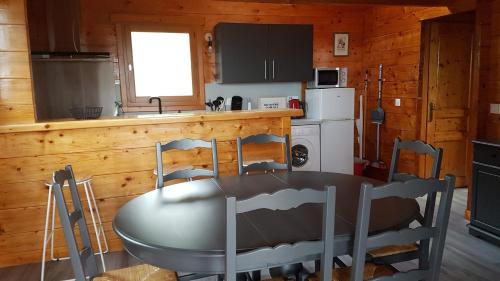 una cocina con mesa y sillas en una cabaña en SUPERBE CHALET AVEC PISCINE CHAUFFEE Juillet et Aout, en Saint-Manvieu-Bocage