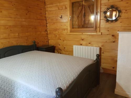 une chambre avec un lit dans une cabane en bois dans l'établissement SUPERBE CHALET AVEC PISCINE CHAUFFEE Juillet et Aout, à Saint-Manvieu-Bocage