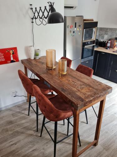 a wooden table in a kitchen with chairs around it at Lumineux Duplex au coeur de l'Isle in LʼIsle-sur-la-Sorgue