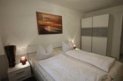 巴貝的住宿－Haus Meeresblick - Ferienwohnung Ostseeperle A 0.13 (Ref. 128670)，卧室配有白色的床和墙上的绘画作品