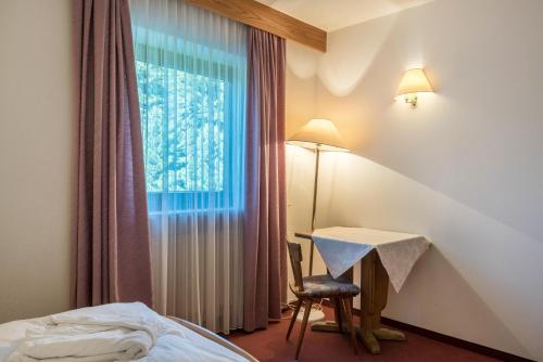 a bedroom with a bed and a desk and a window at Ferienparadies Sabina Schlern in Alpe di Siusi