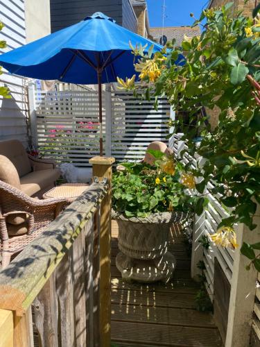 a patio with a blue umbrella and some plants at King Street Accomadation in Margate
