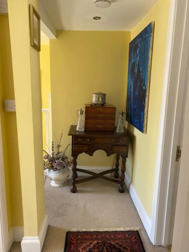 a hallway with a table and a yellow wall at King Street Accomadation in Margate