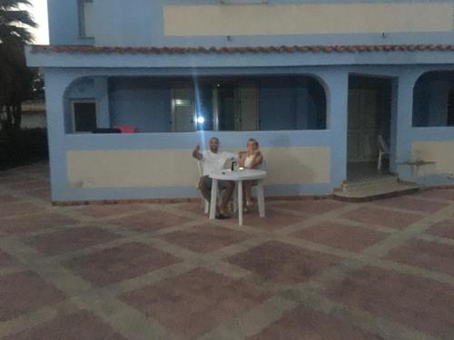 two people sitting at a table in front of a house at Villa Maria Sofia in Realmonte