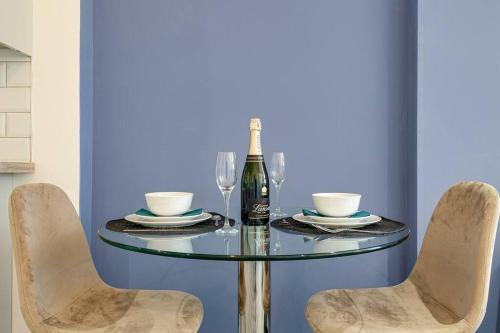 a glass table with a bottle of wine and two chairs at Entire 1 bed apt in the centre of Stockport in Stockport