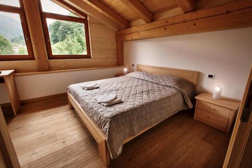 a bedroom with a bed in a wooden house at La Marmote Albergo Diffuso di Paluzza Ronc in Paluzza