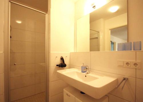 a bathroom with a sink and a shower with a mirror at Haus Meeresblick - Ferienwohnung Strandlaeufer (Ref. 128683) in Baabe