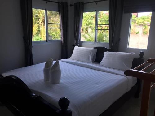 a bedroom with a large bed with two windows at Mew House suanmali lamai in Koh Samui 