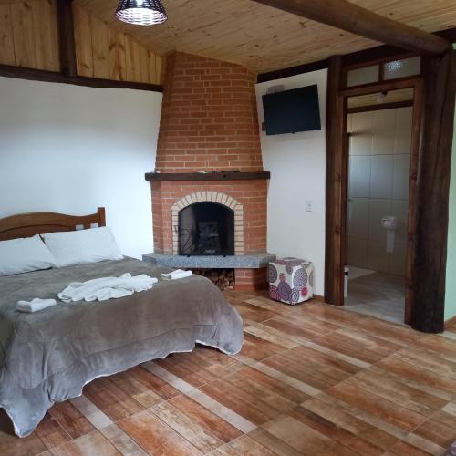 a bedroom with a bed and a brick fireplace at Caminho do Sol in Monte Verde