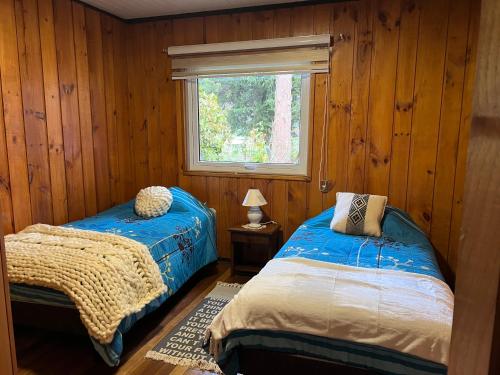 1 dormitorio con 2 camas y ventana en Hostal Casa de Campo Rukaleufu a orillas del Rio Huiscapi, en Villarrica