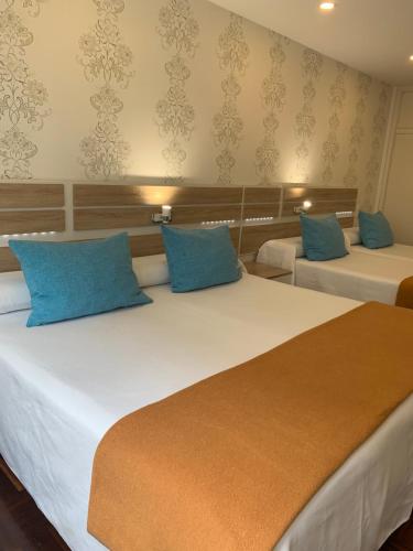 a bedroom with two beds with blue pillows at Hostal San Fernando in Santander