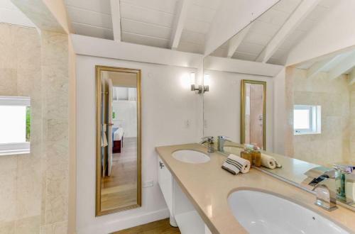 a white bathroom with a sink and a mirror at Westmoreland Cottage in Saint James