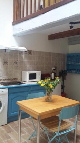 une cuisine avec une table avec un vase de fleurs dessus dans l'établissement La cabane du Petit Matelot, à Honfleur