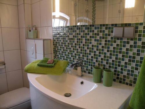 克魯姆赫爾恩的住宿－Apartment Vier Jahreszeiten Pilsum，一间带水槽和绿毛巾的浴室