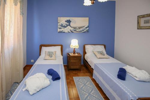 twee bedden in een kamer met blauwe muren bij Casa Vacanza LiHele - Locazione Turistica in Castelsardo