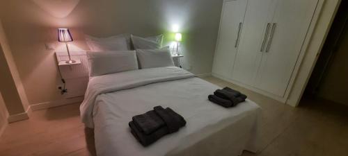 a bedroom with a white bed with two black towels on it at La casa de la luz in Santander