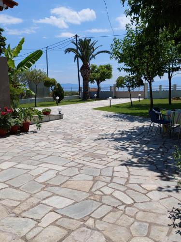 a stone patio with chairs and trees in a park at Platanidia Apartment Pelion in Platanidia