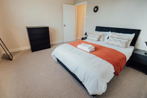 um quarto com uma cama grande e um cobertor laranja em Bellengers Apartments em Kidlington