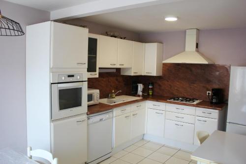 een keuken met witte kasten en witte apparaten bij Maison de 3 chambres avec jardin clos et wifi a Vasles in Vasles