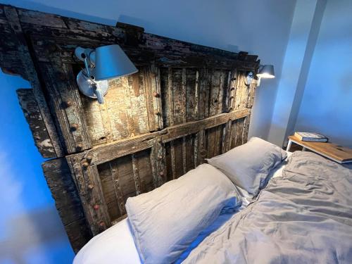 a bed with a wooden headboard with a blue lamp at 3 Zimmer Ferienwohnung Burghof mit Balkon im Herzen Flensburgs in Flensburg