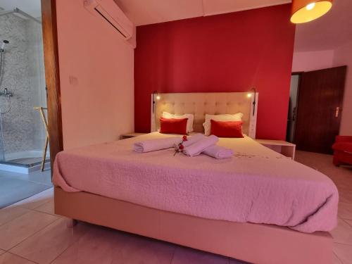 a bedroom with a large bed with pink sheets at Só Mar in Vila Nova de Milfontes