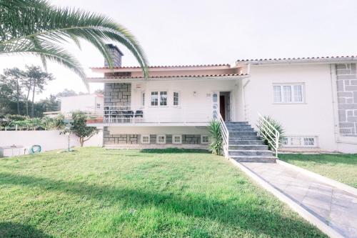 una casa bianca con una palma di fronte di Itaca Experience Playa do Cabedelo a Viana do Castelo