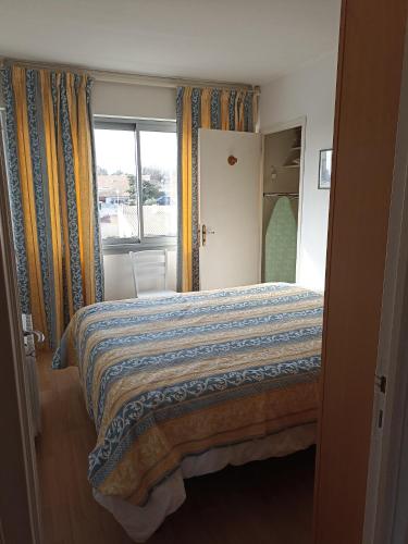 - une chambre dotée d'un lit avec une couverture bleue et jaune dans l'établissement Port panoramique, à Gruissan