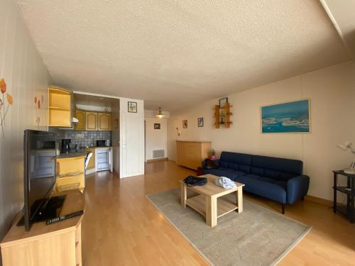 un salon avec un canapé bleu et une cuisine dans l'établissement Port panoramique, à Gruissan