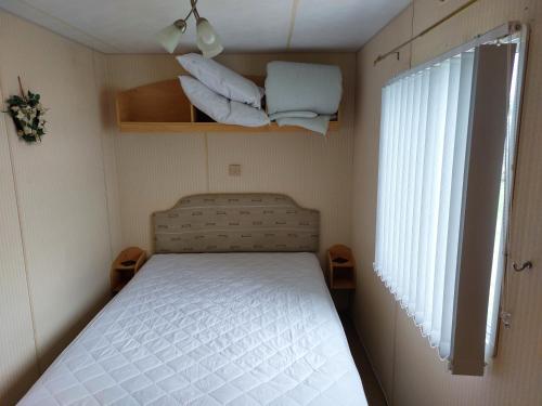 6 berth static caravan, sealands holiday park ingoldmells, skegness في سكيجنيس: غرفة نوم صغيرة بها سرير ونافذة