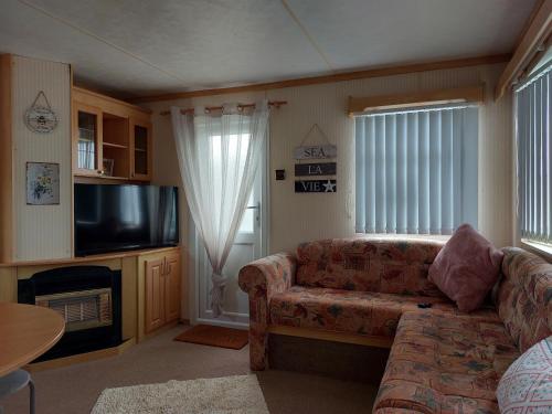 a living room with a couch and a flat screen tv at 6 berth static caravan, sealands holiday park ingoldmells, skegness in Skegness