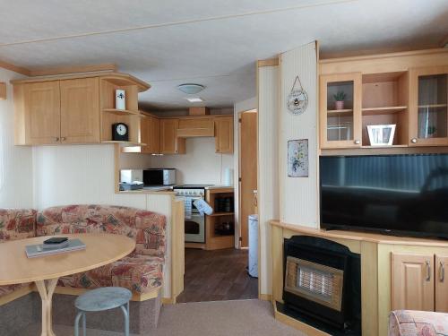 a living room with a couch and a television and a table at 6 berth static caravan, sealands holiday park ingoldmells, skegness in Skegness