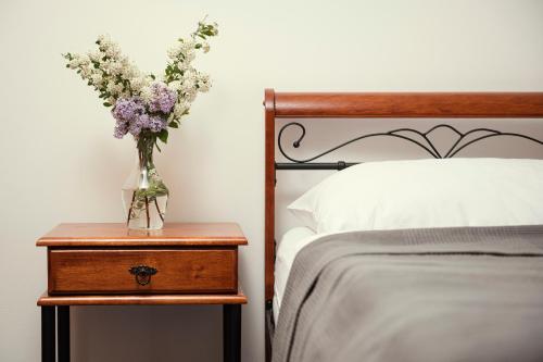 a vase of flowers on a night stand next to a bed at Hotel Ostende in Chocerady